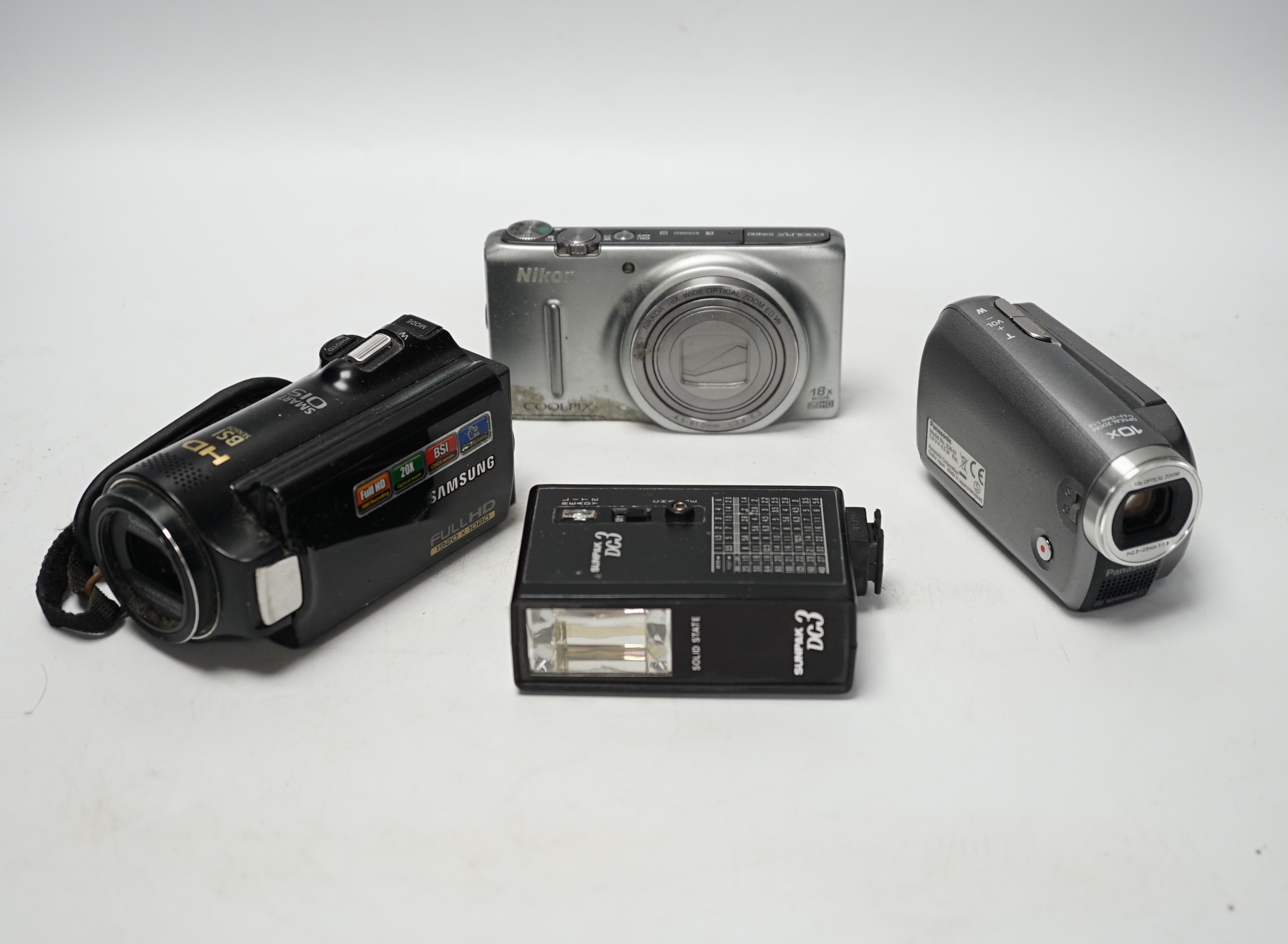A collection of still and video cameras with accessories, including Samsung, Panasonic, Nikon, Cokin, etc.